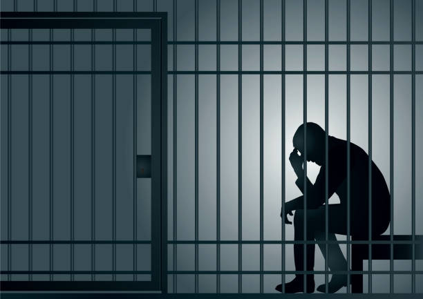 A symbol of a criminal's incarceration with a man imprisoned in a cell. Concept of prison and arrest of an offender or criminal, with a prisoner sitting in his cell holding his head in his hands. murder stock illustrations