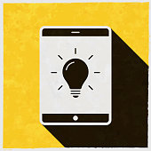 istock Tablet PC with light bulb. Icon with long shadow on textured yellow background 1400136232