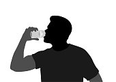 Young man drinking out of a soda can or beer can in silhouette