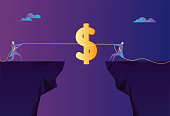istock Two people are tug-of-war on the cliff for dollars 1339847633