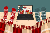 Two people are watching movie or tv program about Santa Claus in Christmas time under the plaid in knitted socks in winter