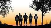 A vector silhouette illustration of a group of five students walking together along a path in a park.  The young men and women wear backpacks and are facign backwards.  There are trees to either side and the sky in the background is an orange gradient.