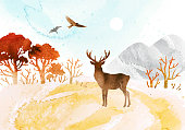 istock Watercolor autumn vector landscape in orange colors. Illustration of mountains, trees, deer ​and birds under blue sky. Silhouette of deer and birds. 1334423313
