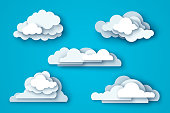 White clouds set isolated on blue sky background. Vector illustration. Layered paper cut style with shadows.
