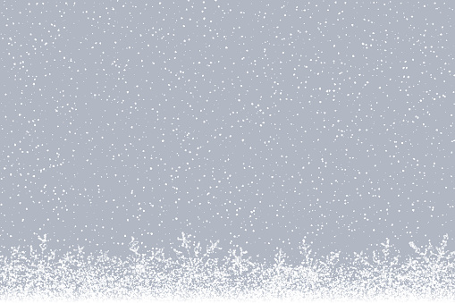 Winter background: Falling snow and snowflakes at the bottom of a desaturated hazy background.