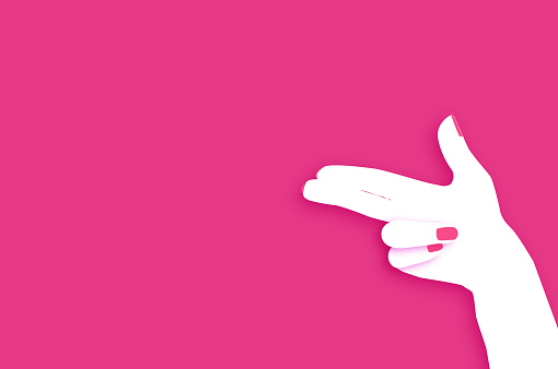 Woman hand making shape of pointed gun. Origami Female holding Two fingers like a revolver. Bang in Paper cut style on pink