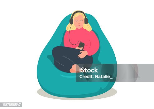 istock Woman in earphones sitting in comfortable bean bag 1187858547