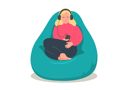 Woman in earphones sitting in comfortable bean bag