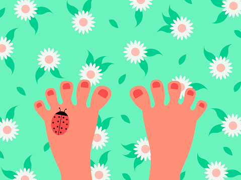 women's feet are standing on the green grass with daisies in close-up