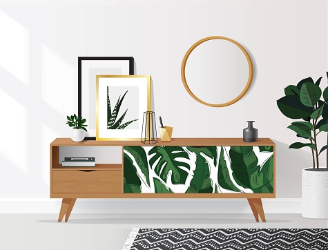 Wooden sideboard with plants and posters on it against white wall.