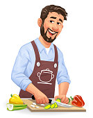 Vector illustration of a laughing young man with a beard standing in the kitchen cutting vegetables, looking at the camera. Concept for cooking, preparing food, healthy eating, healthy lifestyles, vegetarian and vegan food.