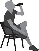 Vector silhouette of a young man drinking a beer while sitting in a chair.
