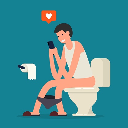 Young man in tie using a smartphone when sitting on toilet bowl.