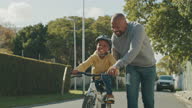 istock 4k video footage of a handsome mature man teaching his son how to ride a bicycle outside 1338028205