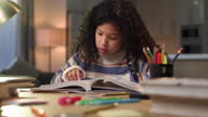 istock 4k video footage of a young girl sitting alone at home and reading a textbook 1329680033