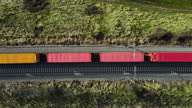 istock Aerial top view of the freight train, carrying colorful containers, moving through the forest at sunset. 4K footage from drone. High quality 4k footage 1304076680