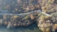 istock Aerial view of car driving in the autumn forest on the winding road next to a lake 1412426841