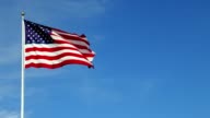 istock American flag waving in the wind in slow motion, with vibrant red white and blue colors against blue sky, with copy space. 1259589085