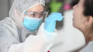 istock asian chinese female doctor with PPE taking mouth swab from patient Coronavirus test. Medical worker in protective suite taking a swab for corona virus test, potentially infected woman 1313084315