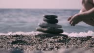 istock Beautiful woman in bikini lays stones on the beach in a balanced way 1400768059