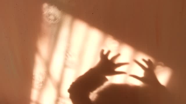 Blur shadows of child hands on wall. Game with light and shadow. Shadow play