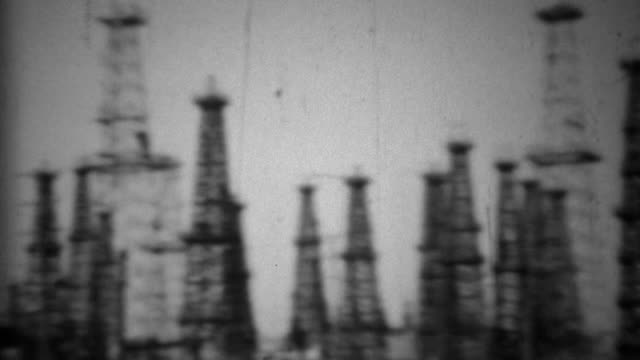 1938: California oil drilling fields steel derrick tower rigging.