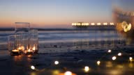istock Candle flame lights in glass, romantic beach date by ocean waves, summer sea. Candlelight on sand. 1324737430