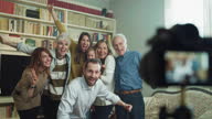 istock Cinematic shot of happy family members  making family photo portrait with photo camera on tripod with timer during a reunion party at home. Concept of memories, happiness, life, emotion, generations. 1362893007