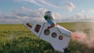 istock Countryside, boy plays in an astronaut helmet in nature with a cardboard model of a space shuttle, a boy runs through a field of rapeseed dreaming of flying into space, pink smoke, 4k slow motion. 1351268170