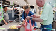 istock Elderly couple making grocery purchase at supermarket 1329542050