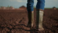 istock A farmer walks across a field in rubber boots on a blurred background of the tractor in motion. Concept of: Rubber boots, Lifestyle, Farmer, Slow Motion, Fields 1223971925
