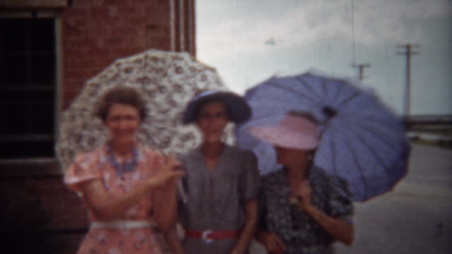 1940: Fashionable women with sun umbrellas and colorful dresses.
