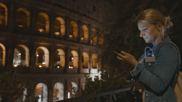 SLO MO Female tourist using her smartphone at the Colosseum at night