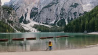 istock Female traveler with a dog contemplating the scenic mountain lake Braies in the Alps during sunset 1348080748