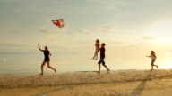istock Happy and carefree childhood. Children playing with older kite, running across the sand, laughing 598875310