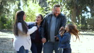 istock Hispanic couple walking in park, joined by two daughters 1349470516