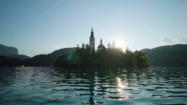 Island with church and forest at back sunlight on Bled lake