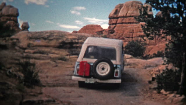 1971: Jeep driver bouldering up a steep incline offroad trail.