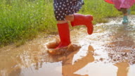 istock SLO MO Little girl in red rain boots running across a muddy puddle 998556872
