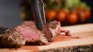 istock Man cut grilled steak with a sharp knife on wooden board 1307285532