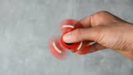 istock Man hand rotating red plastic fidget spinner on marble background. Anti stress toy 1394730320