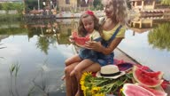 istock Mother and four-year-old blonde daughter eat watermelon on a fishing platform on the river 1334902364