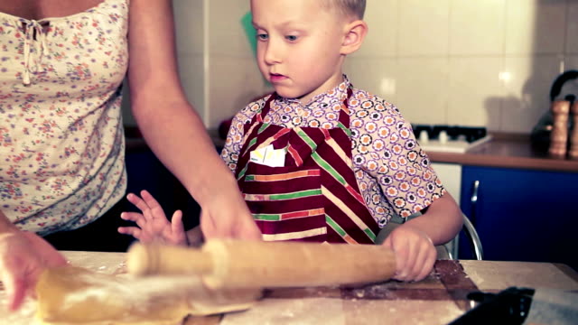 Mother with her little son preparing a dough for the Christmas gingerbread