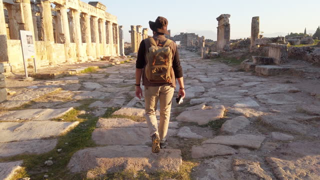 Photographer tourist is walking to the Frontinus Gate in ancient ruins in Hierapolis , Pamukkale