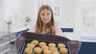 istock Portrait Of Proud Teenage Girl Taking Out Tray Of Homemade Cupcakes From The Oven At Home 1328933782