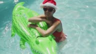 istock Portrait playful woman in Santa hat with crocodile inflatable raft ins sunny summer swimming pool 1089390262