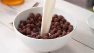istock Pouring Milk to White Bowl Full of Chocolate Ball-Shaped Cereals in Slow Motion 1312345826