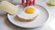 istock Putting egg on avocado toast with cream cheese. Preparing healthy sandwich 1397761736