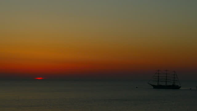 seascape - the last ray of sunset in the sea and the silhouette of an old sailing ship
