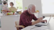 istock Senior man with credit card using laptop at kitchen table 1027758592